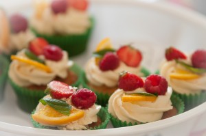 A plate of cupcakes decorated with piped icing and fruit